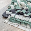 Hoek van een snuffelmat met stroken in wit, lichtgroen en donkergrijs. De rand is donkergrijs met anti-slip noppen.