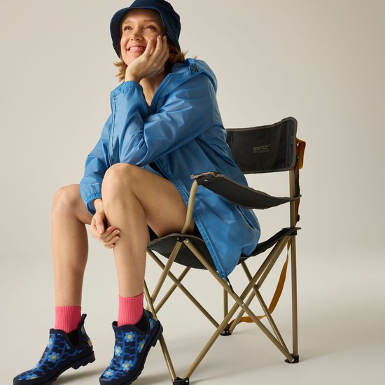 Blauwe lichtgewicht jas met capuchon, gedragen door een zittende vrouw met een blauwe bucket hat en felroze sokken met bloemenlaarzen.