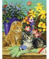 Twee schattige kittens, een oranje en een gestreepte, zittend op een houten ondergrond met bloemen en een speelgoedmuis.