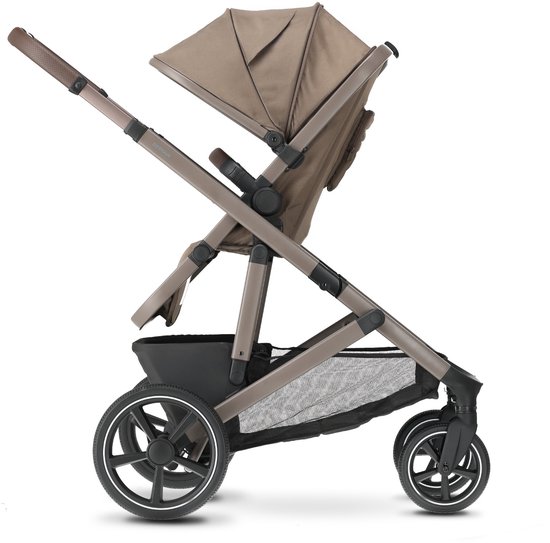 Bruine Deryan kinderwagen met kap en opbergmand, op de grond.