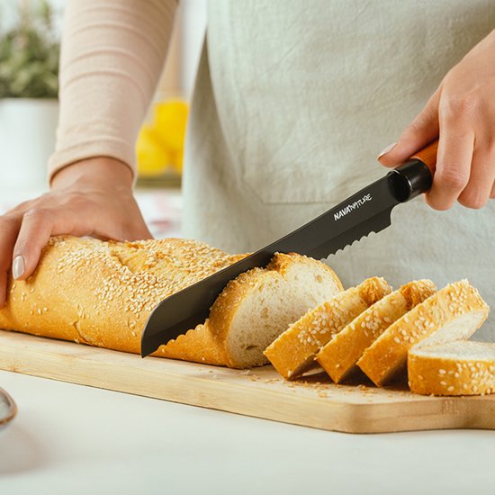 Een NAVA broodmes met zwart gekarteld lemmet snijdt een brood met sesamzaad.