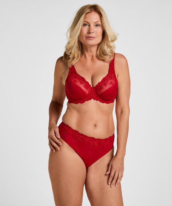 Model met blond haar draagt een rode, niet-voorgevormde beugel-bh met geborduurde bloemen en bijpassende slip.