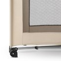 Detail van een beige Deryan campingbedje met gaaswand, metalen frame en zwarte wielen.