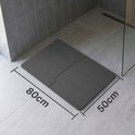 Donkergrijze modulaire badmat van 80x50cm in een hoek van een moderne badkamer.