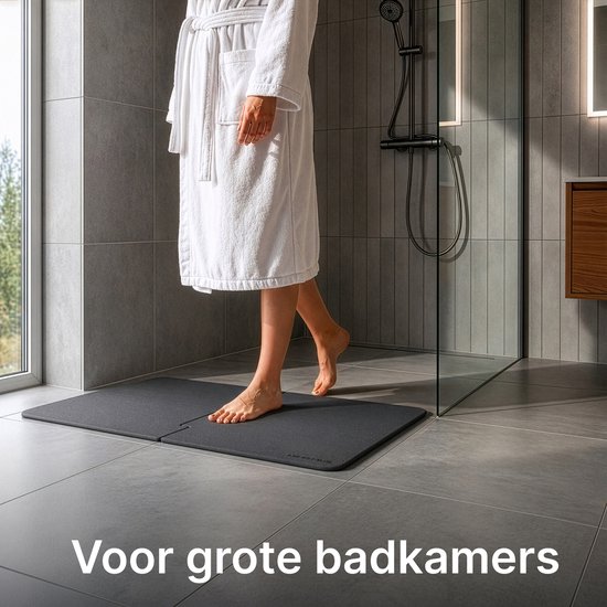 Donkergrijze, modulaire badmat op grijze tegels, naast een douche. Tekst: Voor grote badkamers.