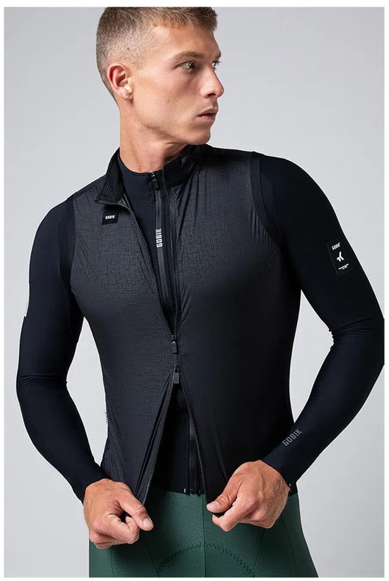 Man met half open zwart GOBIK fietsvest over een zwart fietsshirt met lange mouwen en groene fietsbroek.