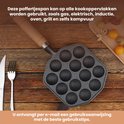 Gietijzeren poffertjespan met 14 holtes en houten handvat, op een houten tafel met bestek en kleine gebakjes.