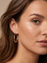 Close-up van een vrouw met gouden oorbel in haar oor, Lundholm Scandinavisch design.