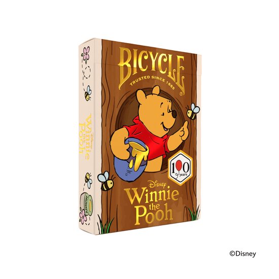 Een speelkaarten doos met Winnie de Poeh die honing uit een potje haalt, met bijen en bloemen. Inclusief 100 jaar logo.