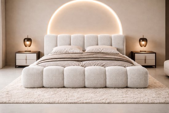 Lichtbeige gestoffeerd bed met een zacht, puffachtig design, twee nachtkastjes en sfeervolle verlichting.
