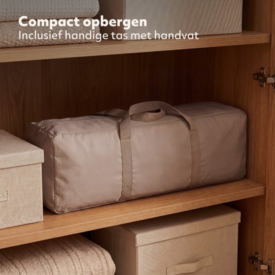 Beige reistas met rits en handvatten, op een plank in een kast. Tekst: 'Compact opbergen'.
