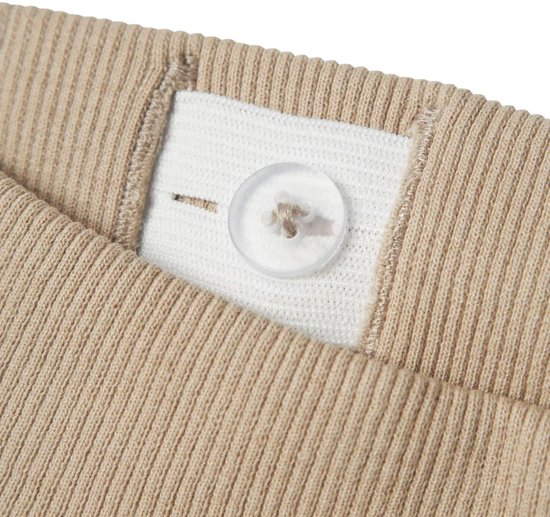 Detail van de tailleband van een beige joggingbroek met een knoop en elastiek.