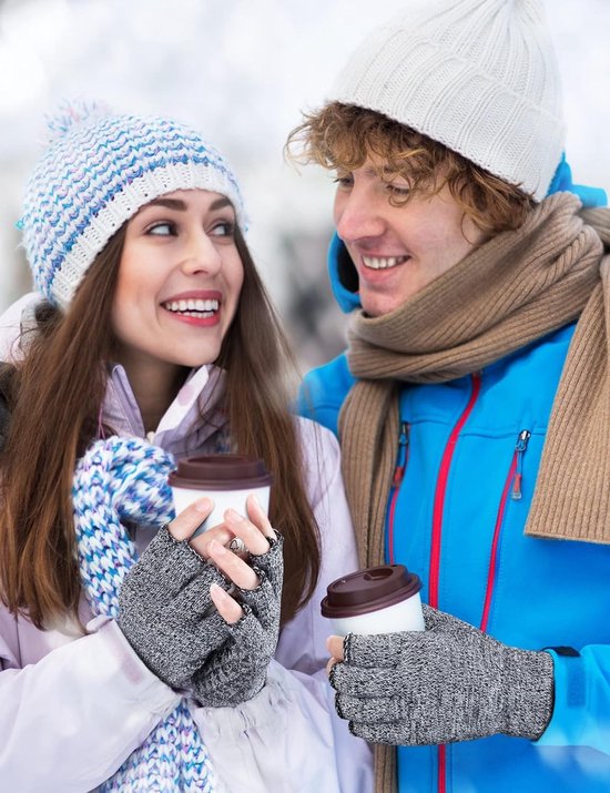 Een man en een vrouw in winterkleding met mutsen en sjaals die grijze vingerloze handschoenen dragen terwijl ze koffie drinken.