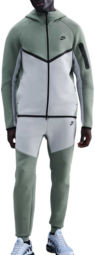 Man staat frontaal in een mintgroene Nike Tech Fleece joggingbroek en hoodie met lichtgrijze en zwarte details.