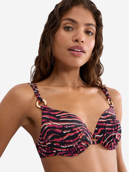 Close-up van een model die een beugelbikini-top met rood-zwart-witte tijgerprint draagt. Goudkleurige ringen bij de bandjes.