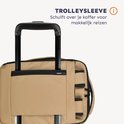 Zandkleurige rugzak met trolley sleeve over de handgreep van een koffer.