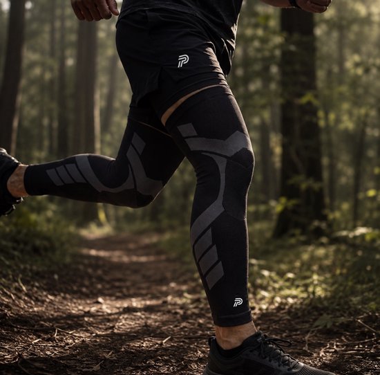 Man hardlopend in een bos, draagt zwarte sportkleding en zwarte compressie knie sleeves met grijs patroon.