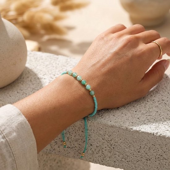 Turquoise koord armband met mintgroene kralen en gouden accenten, gedragen om een vrouwelijke pols.