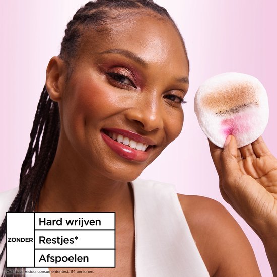 Vrouw met donkere huid en roze oogschaduw, houdt een wattenschijfje met make-up vast. Tekst: Hard wrijven, Restjes, Afspoelen.