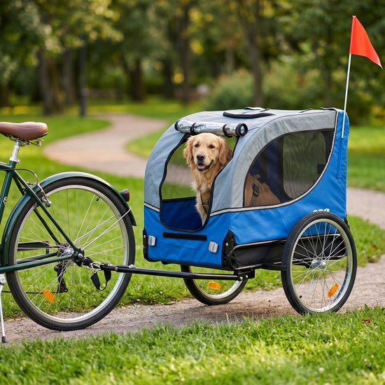 Blauwe fietskar met grijze kap, waarin een golden retriever zit, gekoppeld aan een fiets.