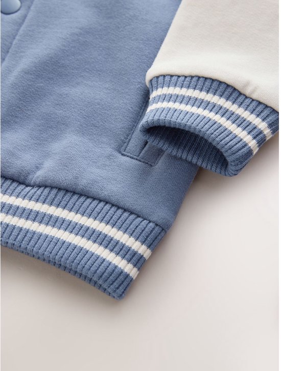 Detail van de gestreepte boord en mouw van het blauw-witte bomberjack.