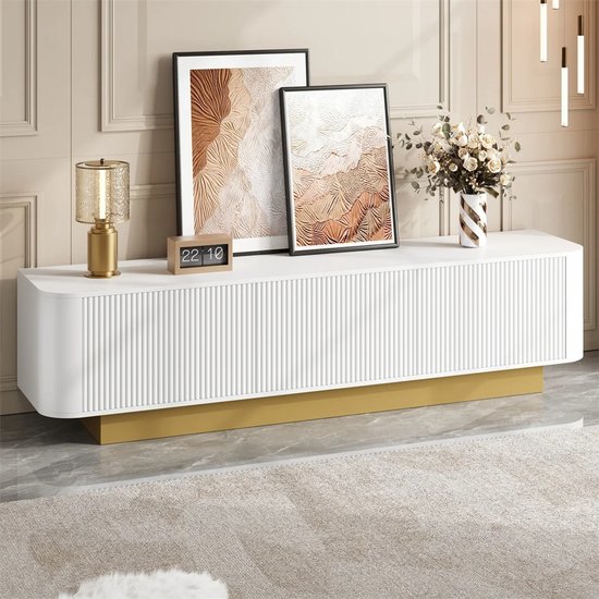 Witte dressoirkast met gouden voet en ribbeldeuren, met decoratie ernaast.