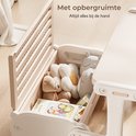 Beige kinderbureau met opbergruimte, gevuld met knuffels en een boek.