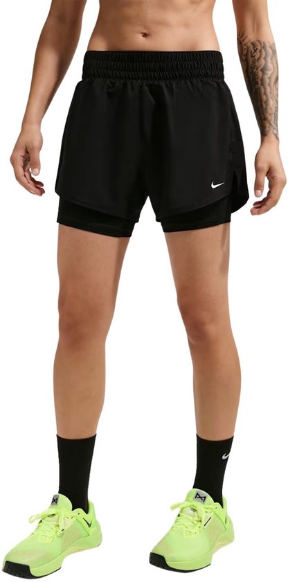 Model draagt zwarte Nike shorts met ingebouwde slips en felgekleurde schoenen.