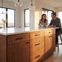 Keukeneiland met houten deuren en ladefronten, voorzien van zwarte stanggrepen.