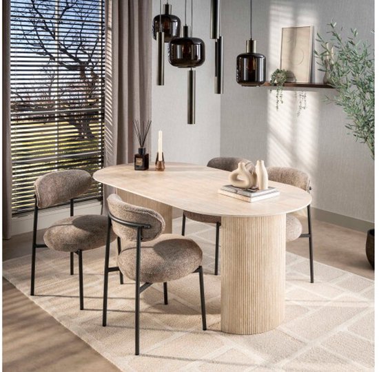 Ovale eettafel met beige, getextureerd tafelblad en een gedetailleerde poot. Vier stoffen eetkamerstoelen staan rond de tafel.