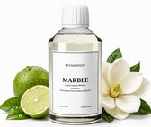 Flesje SteamStory 'Marble' wasparfum omringd door verse limoenen, witte bloesems en groene bladeren met waterdruppels.