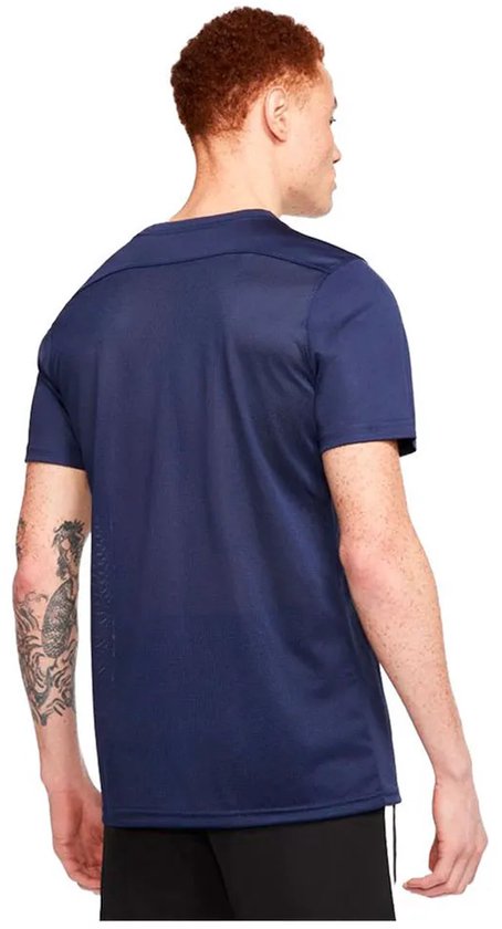 Man met kort rood haar, gezien van achteren, draagt een marineblauw sportshirt met korte mouwen. Getatoeëerde arm.