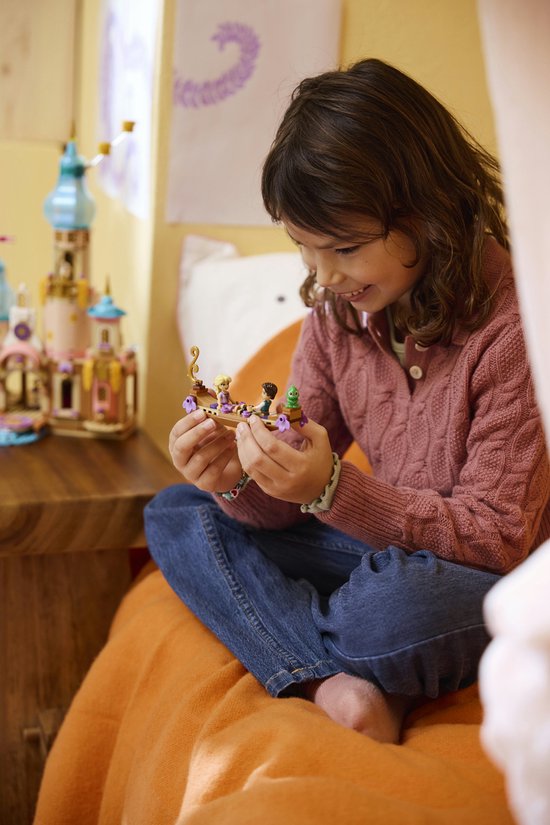 Meisje met donkerbruin haar in roze gebreide vest speelt met LEGO kasteel onderdelen.