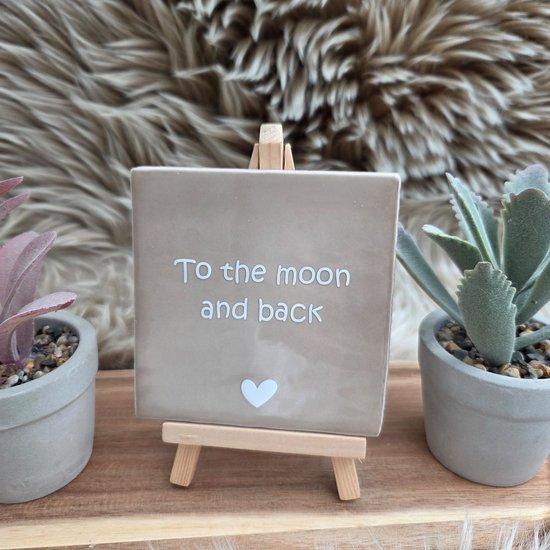 Carreau décoratif beige clair avec le texte 'To the moon and back' et un cœur, sur un chevalet.
