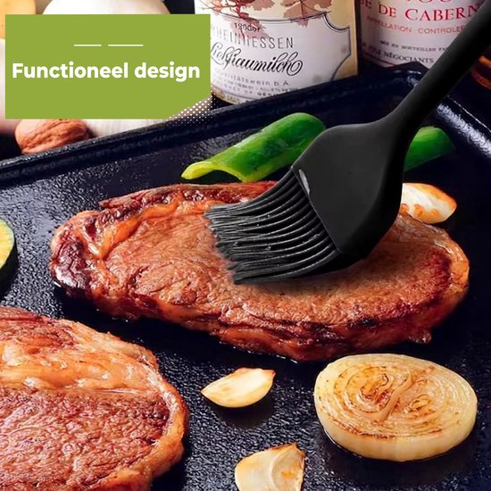 Un pinceau de cuisine en silicone noir est utilisé pour badigeonner un steak sur une plaque de cuisson.