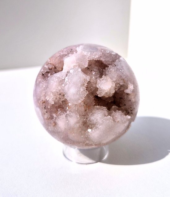 Sphère d'agate rose pâle avec un intérieur brut et cristallin.