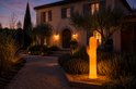 Oranje cactuslamp verlicht de oprit van een landhuis.