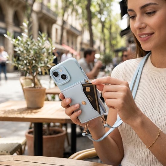 Vrouw haalt pasje uit lichtblauw telefoonhoesje met portemonnee en rits, buiten op een terras.