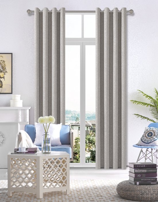 Grijze, verduisterende gordijnen met ringen en een subtiel metallic patroon, hangend voor een raam in een woonkamer.
