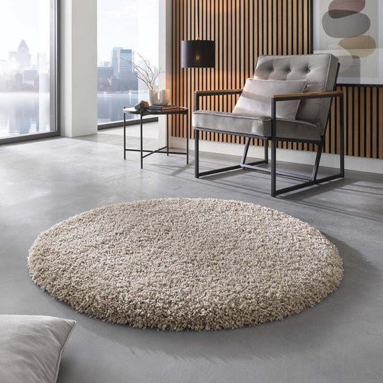 Een ronde, beige shaggy vloerkleed in een stijlvolle woonkamer.