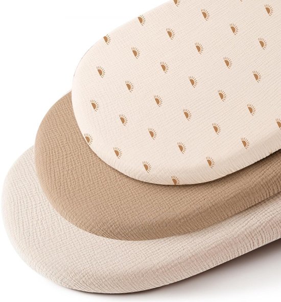Drie op elkaar gestapelde wieghoeslakens: een met zonneprint, een beige en een lichtbruine.