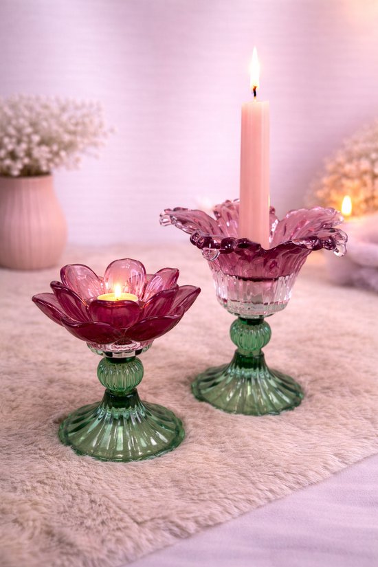 Twee glazen kandelaars in bloemvorm. De ene met een roze kaars, de andere met een waxinelichtje.
