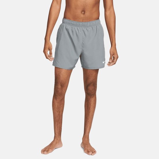 Man met een grijze Nike hardloopshort, staand, met het Nike logo op de rechterpijp.