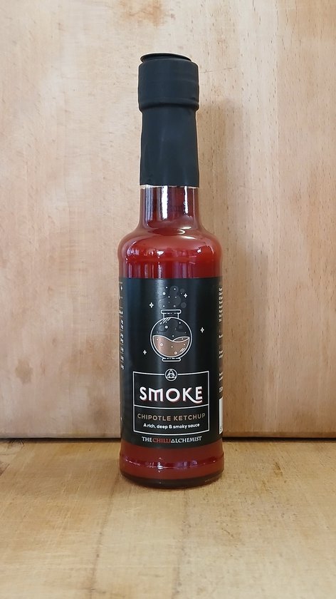 Bouteille de ketchup chipotle rouge avec étiquette noire : "SMOKE CHIPOTLE KETCHUP A rich, deep & smoky sauce" et une fiole avec de la fumée.