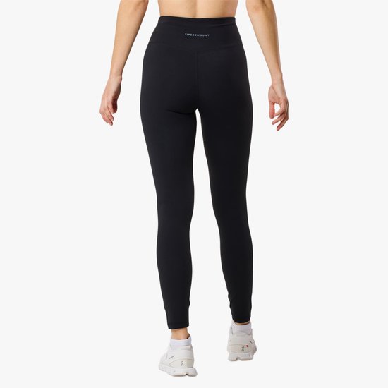 Zicht op de achterkant van een vrouw in zwarte legging met wit logo op de tailleband.