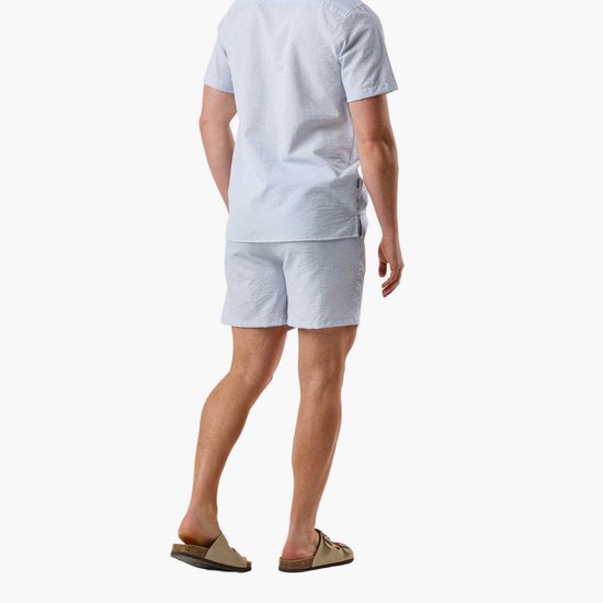 Man van achteren, draagt lichtblauwe gestreepte seersucker pyjamaset.