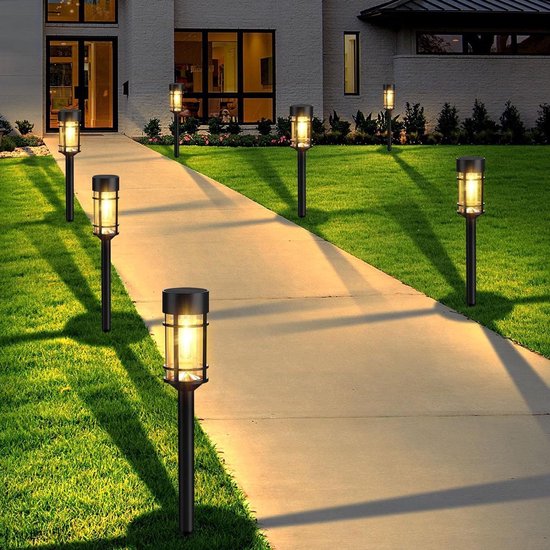 Verlicht pad met meerdere zwarte lantaarnpalen met filament LED, langs een modern huis.