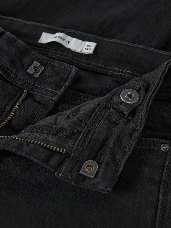 Sluiting van zwarte jeans met rits en knoop. Label met '10Y 140'.
