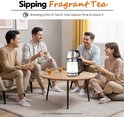 Vier lachende vrienden zitten rond een salontafel met een glazen waterkoker met thee-infuus. De waterkoker heeft roestvrijstalen accenten en een zwarte handgreep. Iedereen heeft een theeglas.