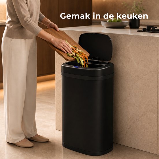Zwarte sensor prullenbak met open deksel, waar een persoon groenteafval in gooit.